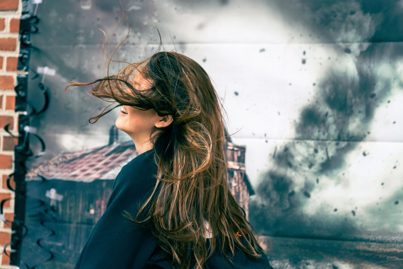 A person with long hair blowing across their face